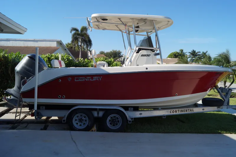 The Image of 2014 Century 2200 Center Console boat on trailer, red and white design, parked outdoors. - 0