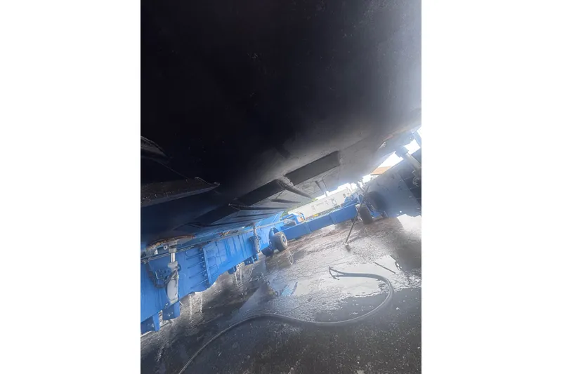 Slide: The Image of Underneath view of a 2007 Progressive Industrial machinery with blue components and wet ground. - 16