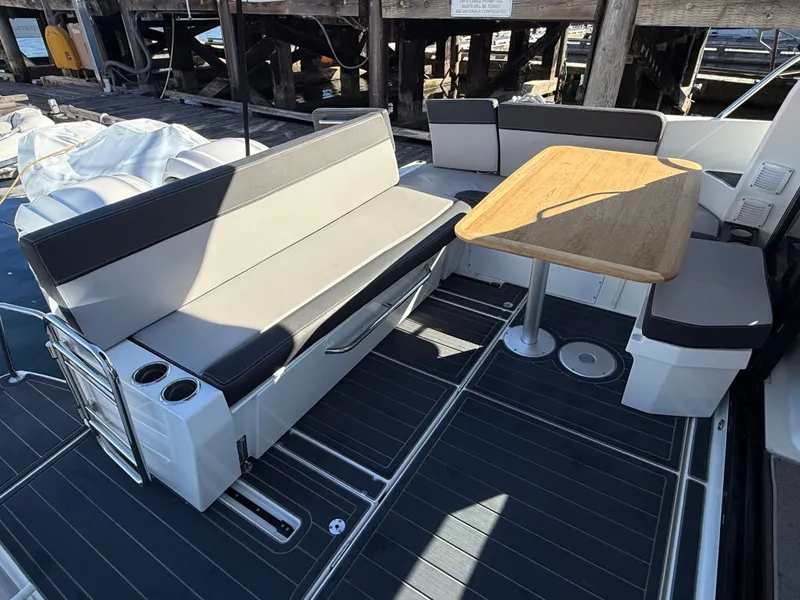 Slide: The Image of The image shows the cockpit of a 2024 Jeanneau NC 1095 Coupe with gray seating and a wooden table. - 13