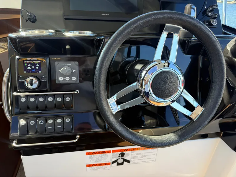 Slide: The Image of The image shows the helm of a 2024 Jeanneau NC 1095 Coupe with a shiny chrome steering wheel. - 29
