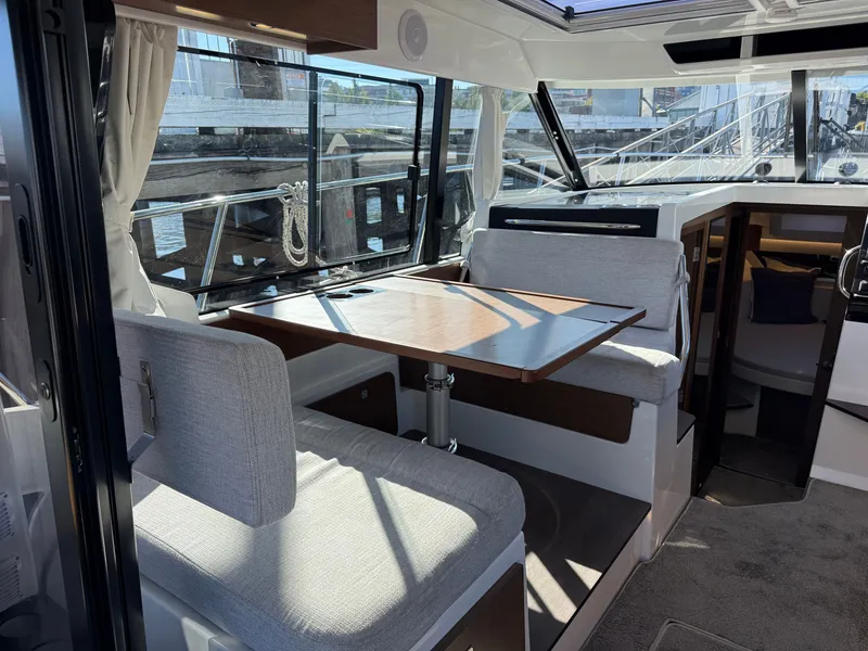 Slide: The Image of Interior of a 2024 Jeanneau NC 1095 Coupe with a dining table and bench seating. - 18