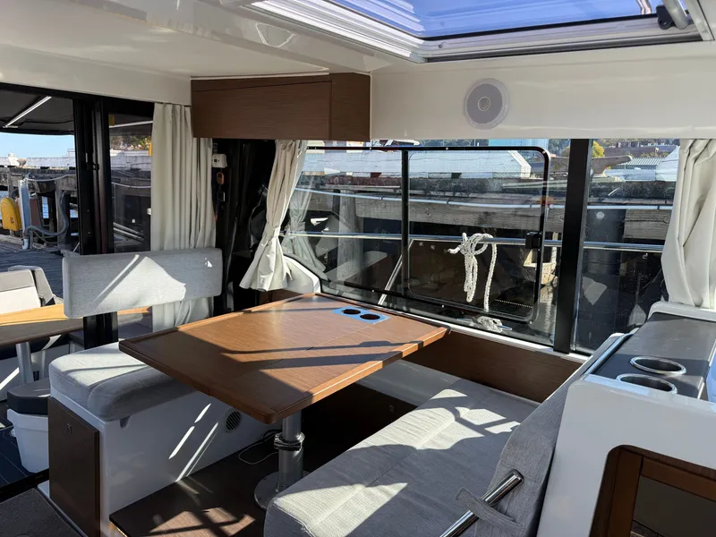 Slide: The Image of Interior of the 2024 Jeanneau NC 1095 Coupe with dining table, gray upholstery, and large windows. - 20