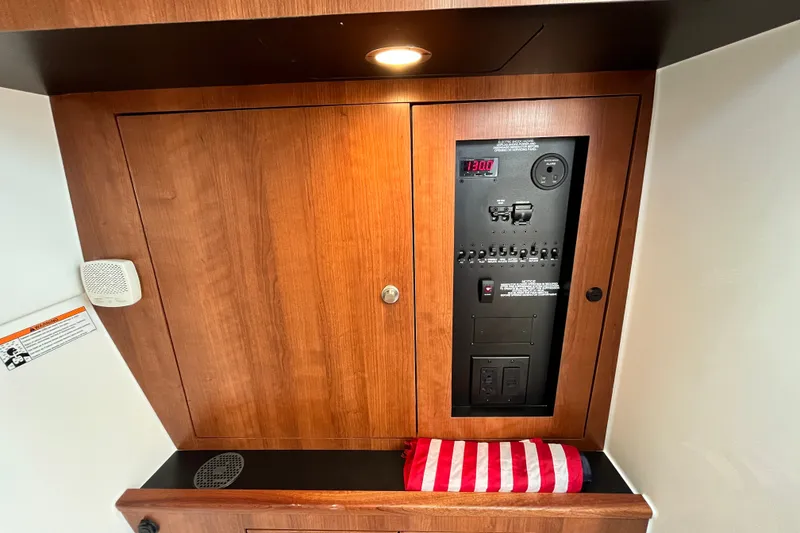 Slide: The Image of Control panel inside 2027 Pursuit DC 326 Dual Console boat, featuring wood finish and American flag towel. - 20