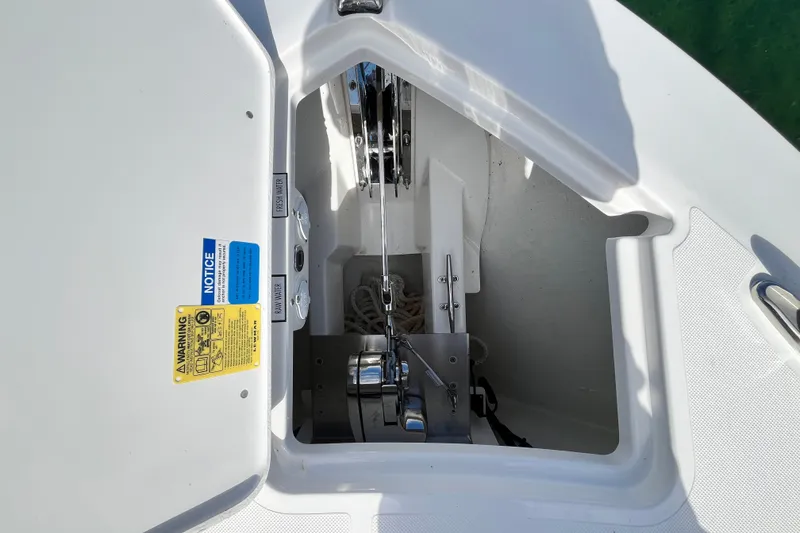 Slide: The Image of Anchor compartment of 2027 Pursuit DC 326 Dual Console boat, featuring safety labels and equipment. - 22