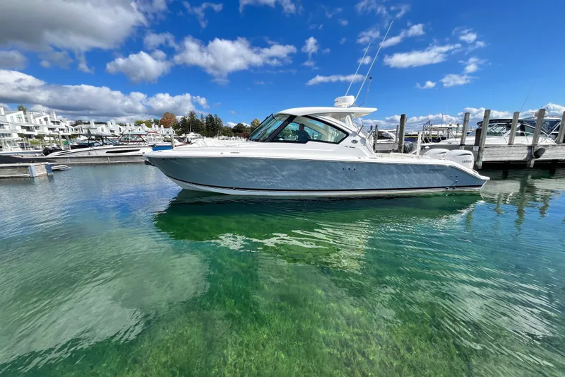 The Image of 2027 Pursuit DC 326 Dual Console boat docked in clear water under a blue sky. - 0