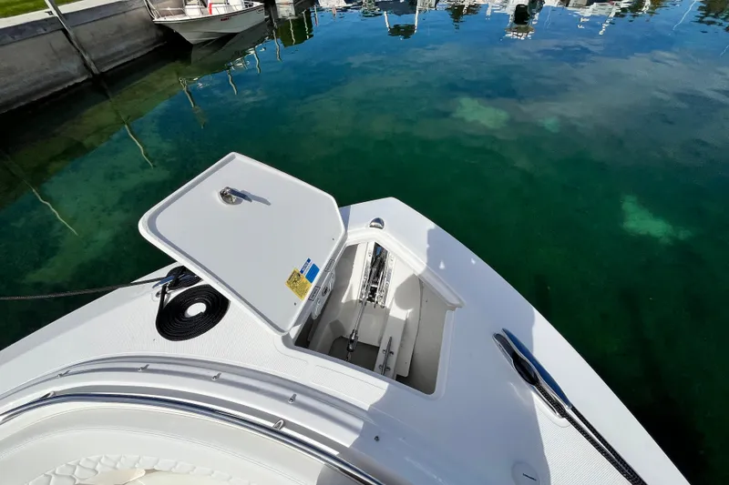 Slide: The Image of Open anchor compartment on 2027 Pursuit DC 326 Dual Console boat, docked by clear water. - 23