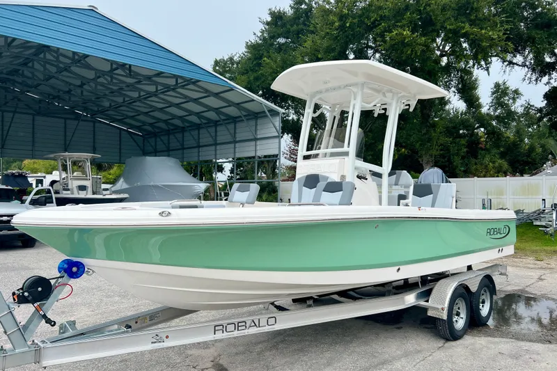 The Image of 2027 Robalo 226 Cayman boat on trailer, parked under a metal canopy. - 1
