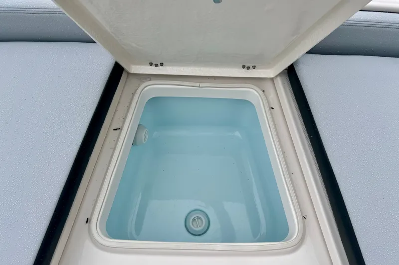 Slide: The Image of Open storage compartment on 2027 Robalo 226 Cayman boat, featuring a clean interior. - 19