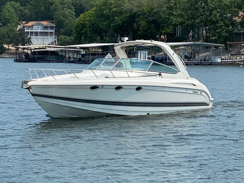 The Image of A white motor yacht cruising on a calm lake, surrounded by trees and houses. - 0