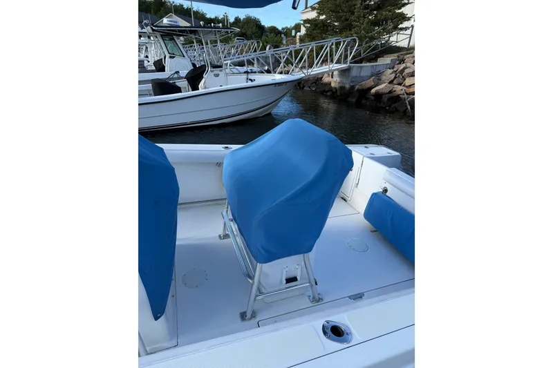 Slide: The Image of 2005 Edgewater 245CC boat interior with blue seat covers, docked near other boats. - 16