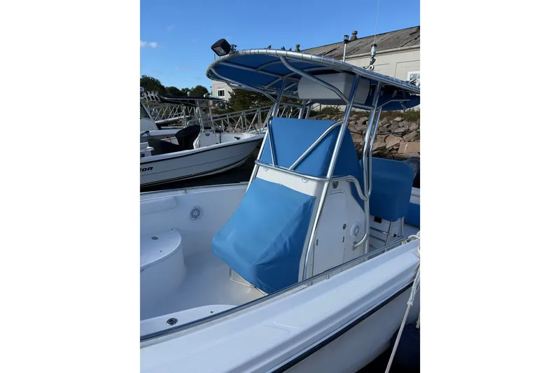 Slide: The Image of 2005 Edgewater 245CC boat with blue seating and canopy, docked near other boats. - 15