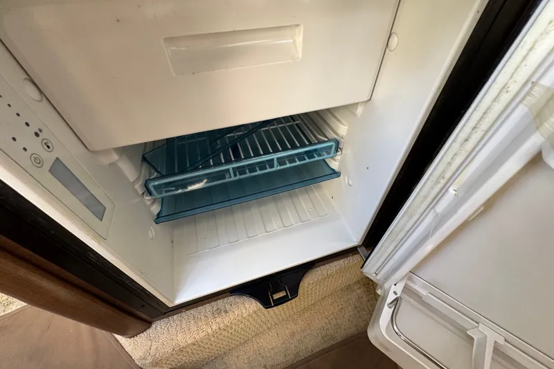 Slide: The Image of Open refrigerator inside 2018 Sea Ray Sundancer 260 boat, showing empty shelves. - 44