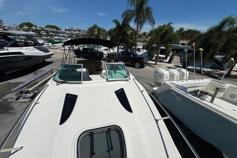 Slide: The Image of 2018 Sea Ray Sundancer 260 docked, surrounded by palm trees and other boats. - 80