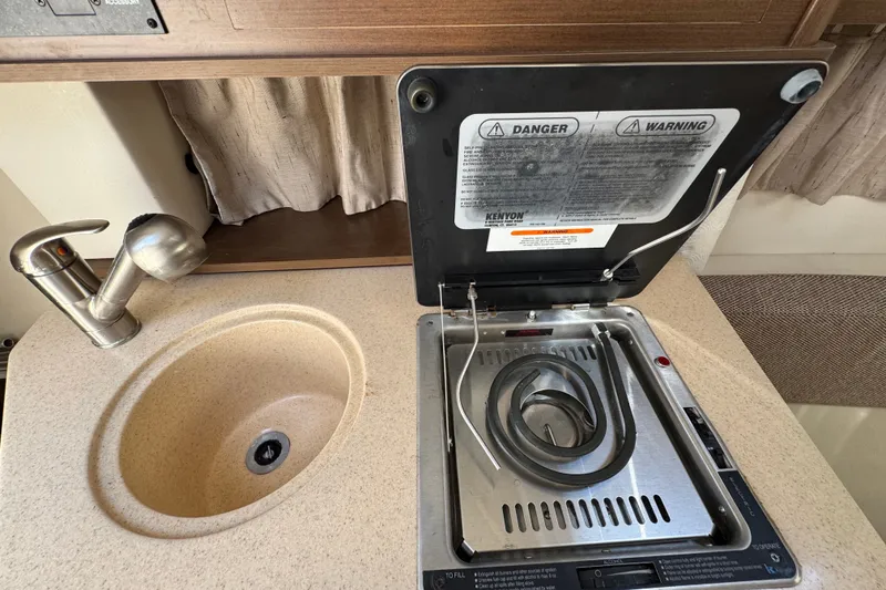 Slide: The Image of 2018 Sea Ray Sundancer 260 galley with sink and stove, featuring safety warnings. - 41