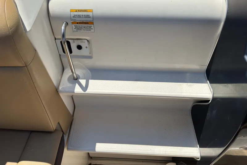Slide: The Image of Steps on a 2018 Sea Ray Sundancer 260 boat, featuring a safety handle and warning label. - 73