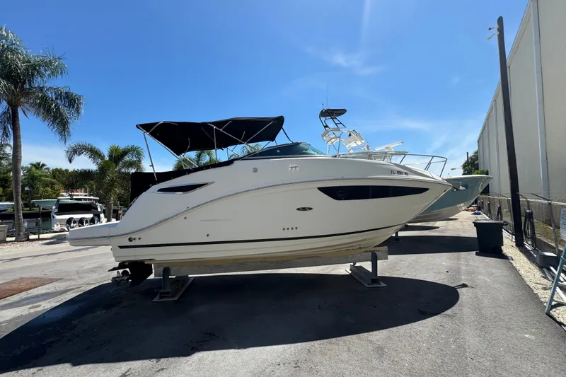 The Image of 2018 Sea Ray Sundancer 260 boat on dry dock, sunny day, palm trees in background. - 0