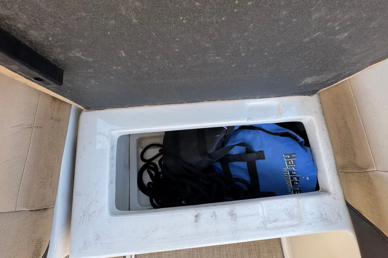 Slide: The Image of Storage compartment on a 2018 Sea Ray Sundancer 260 with blue bag and black rope. - 70