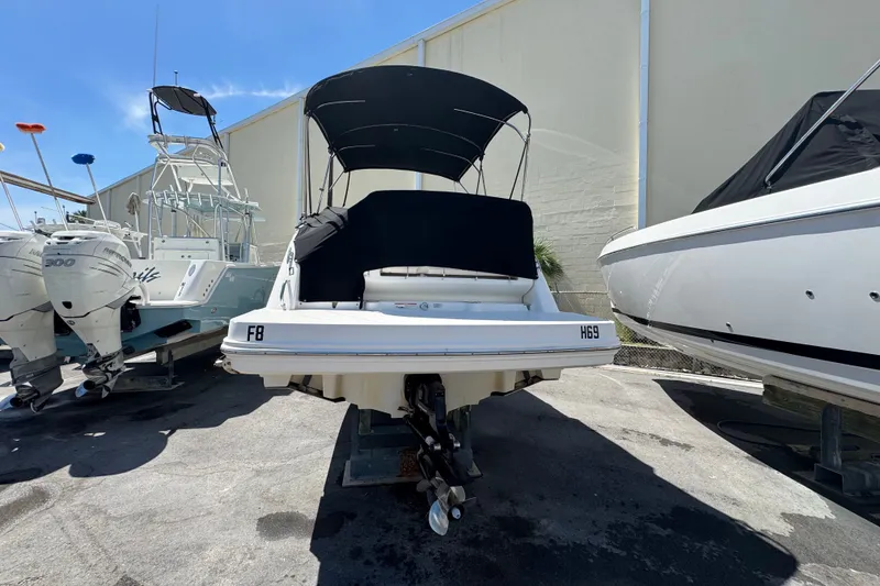 Slide: The Image of 2018 Sea Ray Sundancer 260 boat with black canopy, docked between other boats. - 5