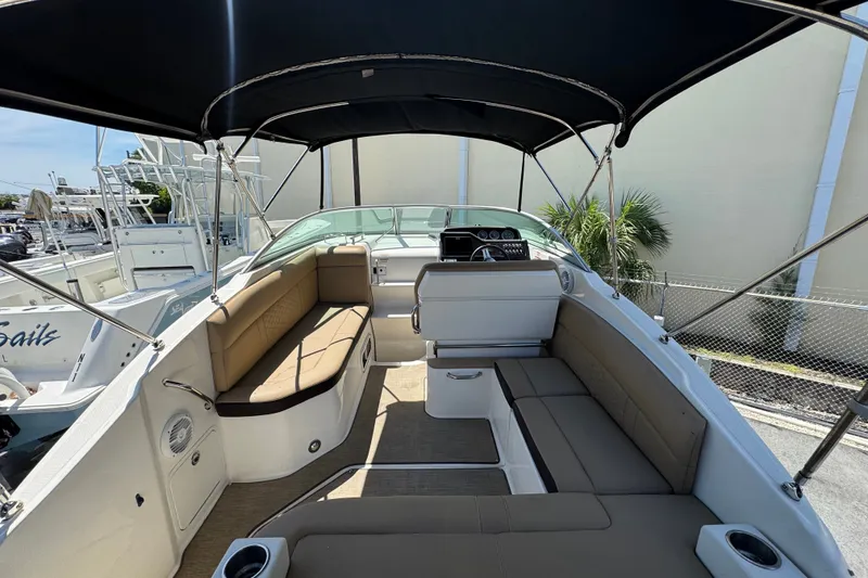 Slide: The Image of 2018 Sea Ray Sundancer 260 boat interior with seating and canopy, docked outdoors. - 23
