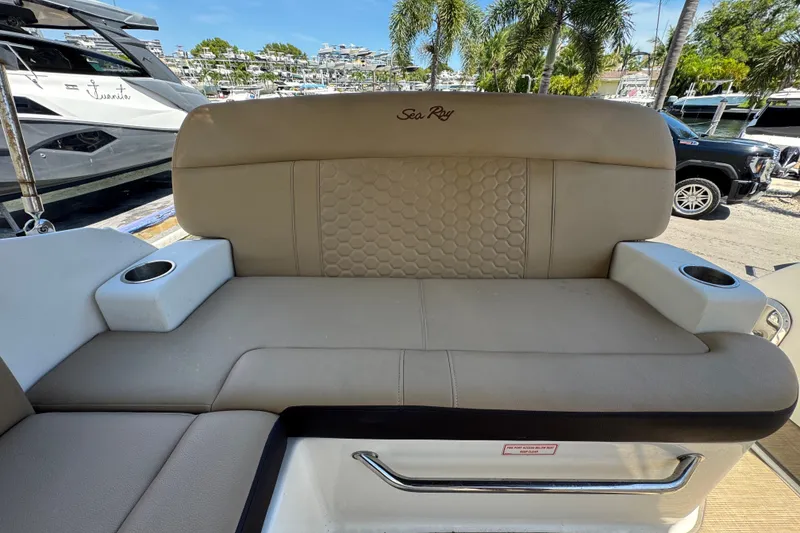 Slide: The Image of 2018 Sea Ray Sundancer 260 boat seating with cup holders, docked near palm trees. - 26