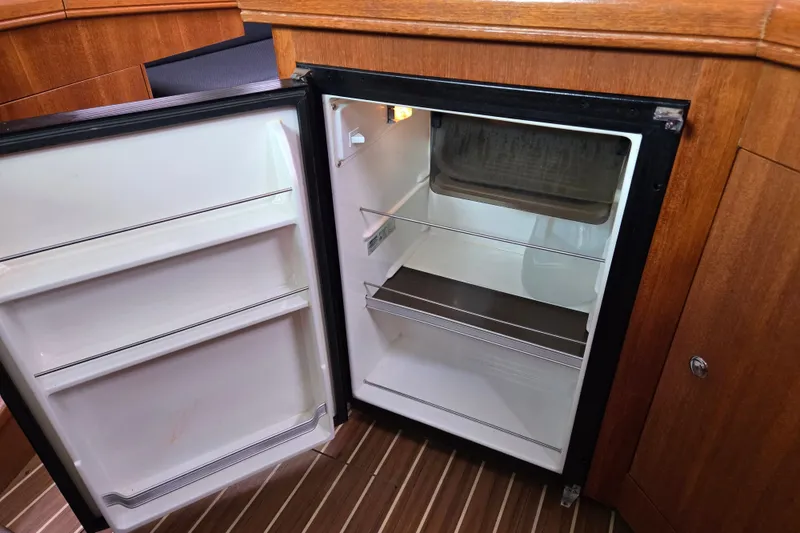 Slide: The Image of Open refrigerator inside a 2006 Hunter 36 yacht, featuring wooden cabinetry. - 26