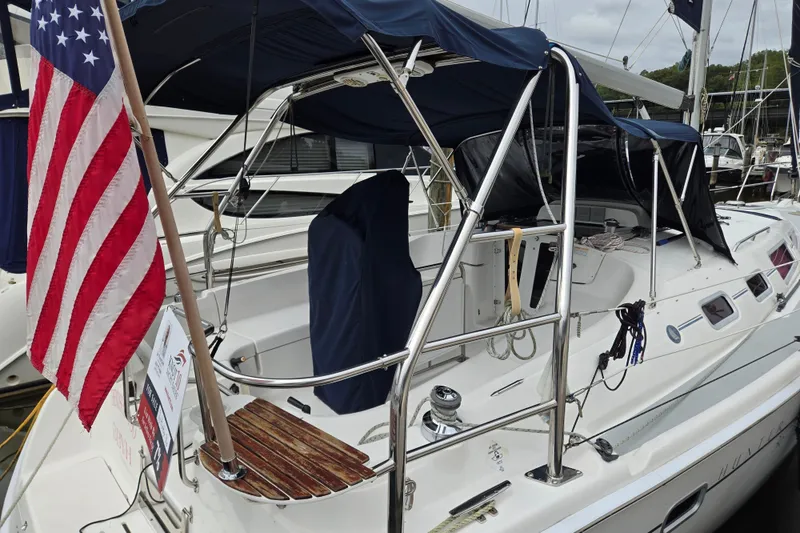 Slide: The Image of 2006 Hunter 36 sailboat with American flag, docked at marina, featuring covered cockpit. - 46