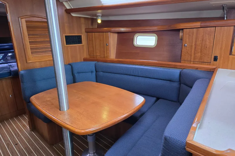 Slide: The Image of Interior of 2006 Hunter 36 sailboat with wooden table and blue cushioned seating. - 13
