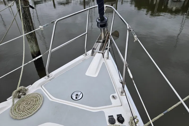 Slide: The Image of Bow of a 2006 Hunter 36 sailboat with ropes and railing, docked on calm water. - 6