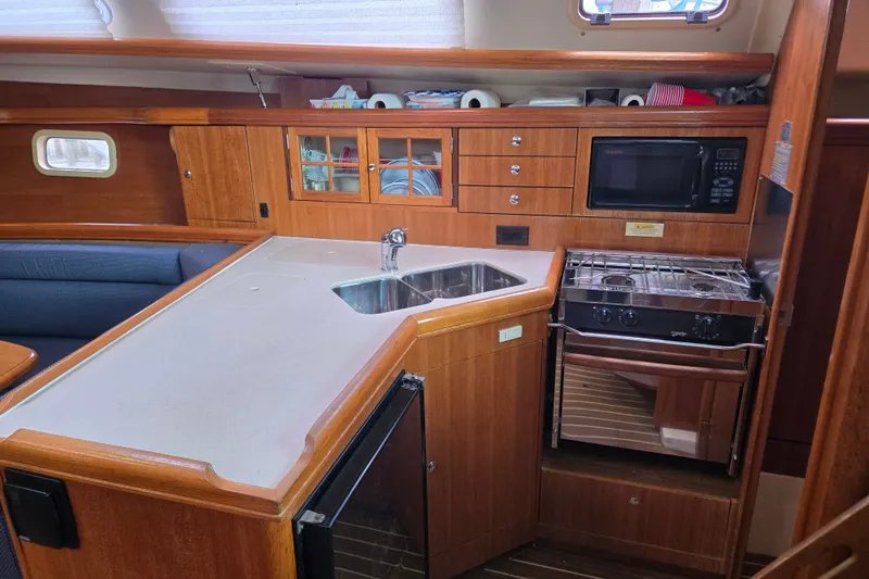 Slide: The Image of 2006 Hunter 36 yacht kitchen with wood cabinetry, sink, stove, and microwave. - 24