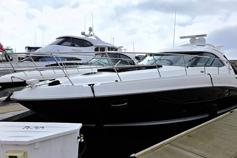 The Image of 2012 Sea Ray 410 Sundancer yacht docked at marina under cloudy sky. - 0