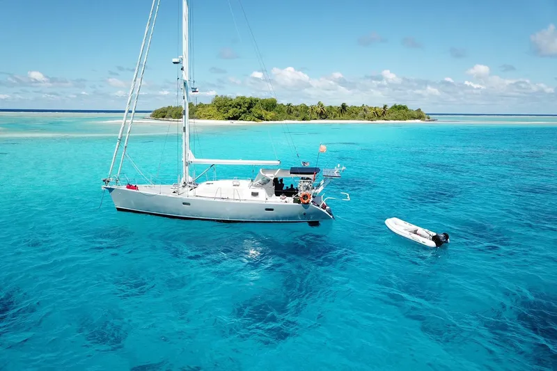 Slide: The Image of A 2000 Garcia 48 Raised Salon yacht sails in clear turquoise waters near a tropical island. - 1