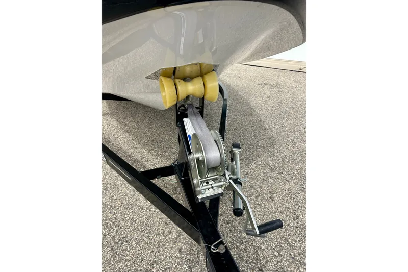Slide: The Image of 2022 Scarab 215 ID boat trailer with winch and yellow roller on pavement. - 63