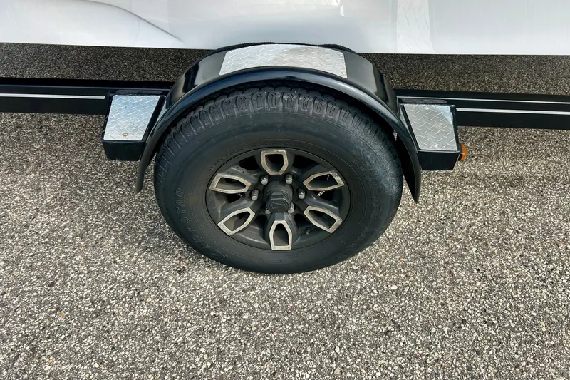 Slide: The Image of Trailer wheel of 2022 Scarab 215 ID on textured pavement. - 60