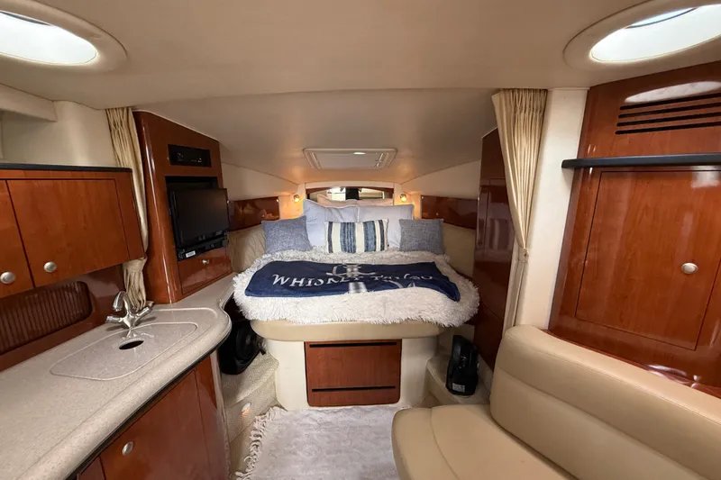 Slide: The Image of Interior of 2006 Sea Ray Sundancer 320, featuring cozy cabin with bed and wooden cabinetry. - 28