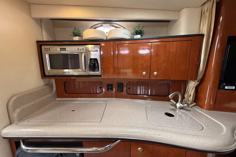 Slide: The Image of 2006 Sea Ray Sundancer 320 galley with microwave, sink, and wooden cabinetry. - 30