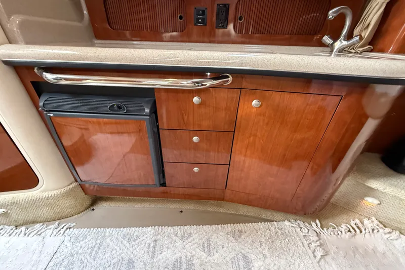 Slide: The Image of 2006 Sea Ray Sundancer 320 interior kitchenette with wood cabinetry and compact fridge. - 31