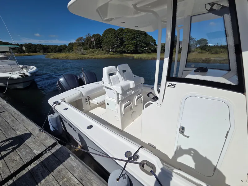 Slide: The Image of A 2020 Regulator 25 boat docked. It features two seats and twin outboard engines. - 8