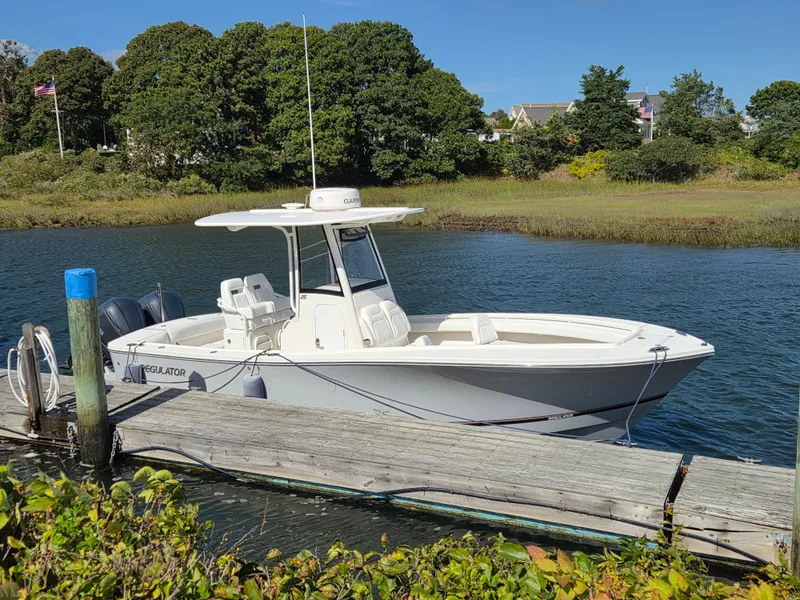 Slide: The Image of A white 2020 Regulator 25 boat docked at a wooden pier in calm waters. - 2