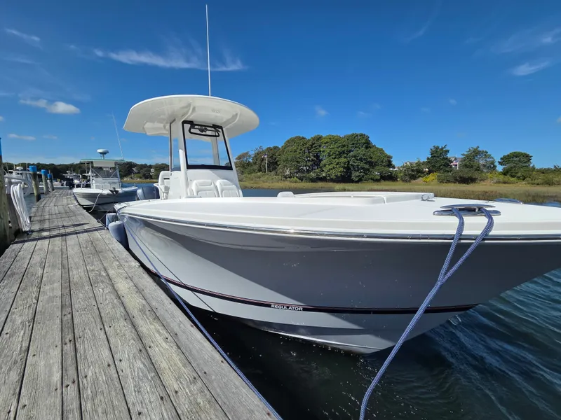 The Image of A 2020 Regulator 25 boat docked at a wooden pier. The sky is clear and blue. - 1