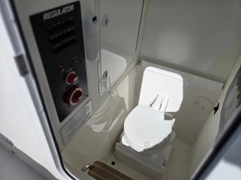 Slide: The Image of The image shows a compact boat toilet with control panel in a 2020 Regulator 25. - 18
