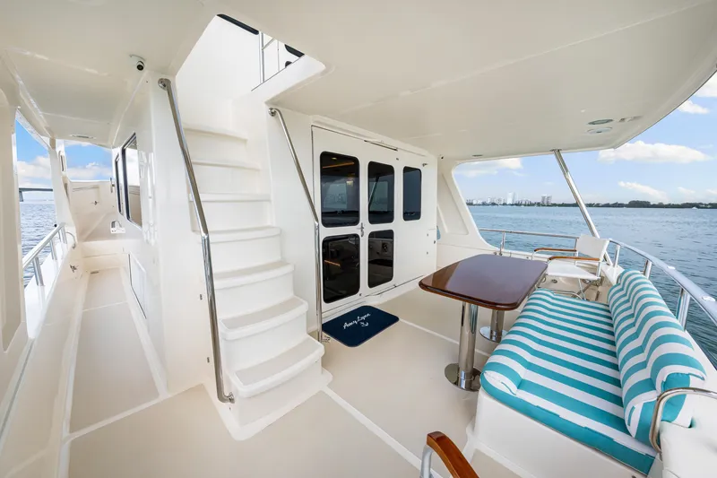 Slide: The Image of 2017 Marlow Explorer 49E yacht deck with striped seating, table, and ocean view. - 16