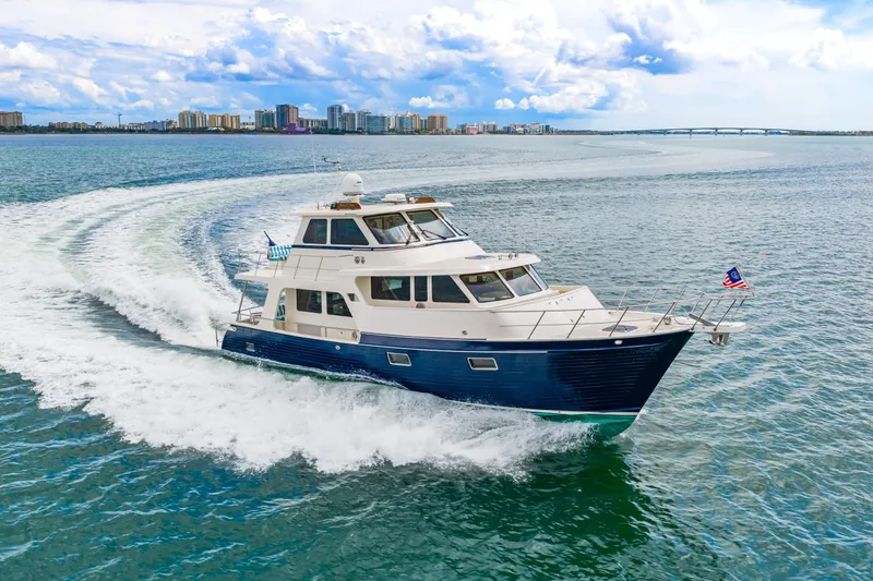 Slide: The Image of 2017 Marlow Explorer 49E yacht cruising on open water with city skyline backdrop. - 3