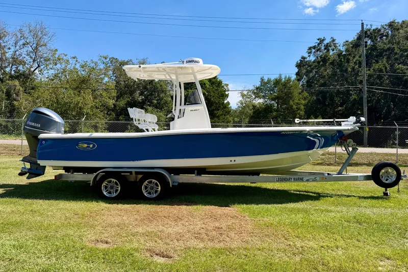 Slide: The Image of 2017 Sea Hunt BX25BR boat on trailer, blue hull, Yamaha engine, parked on grass. - 2
