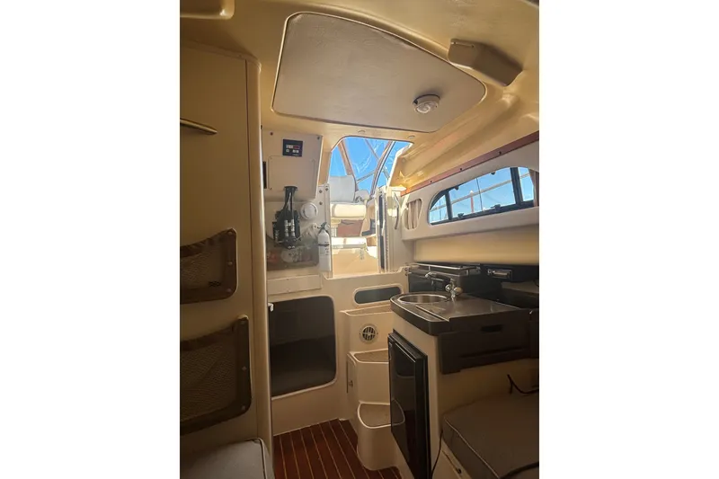 Slide: The Image of Interior of 2005 Grady White 282 Sailfish boat, featuring compact kitchen and seating area. - 27