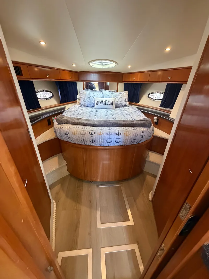 Slide: The Image of The cabin of the 2000 Carver 396 Motor Yacht features a cozy bed with nautical-themed bedding. - 46