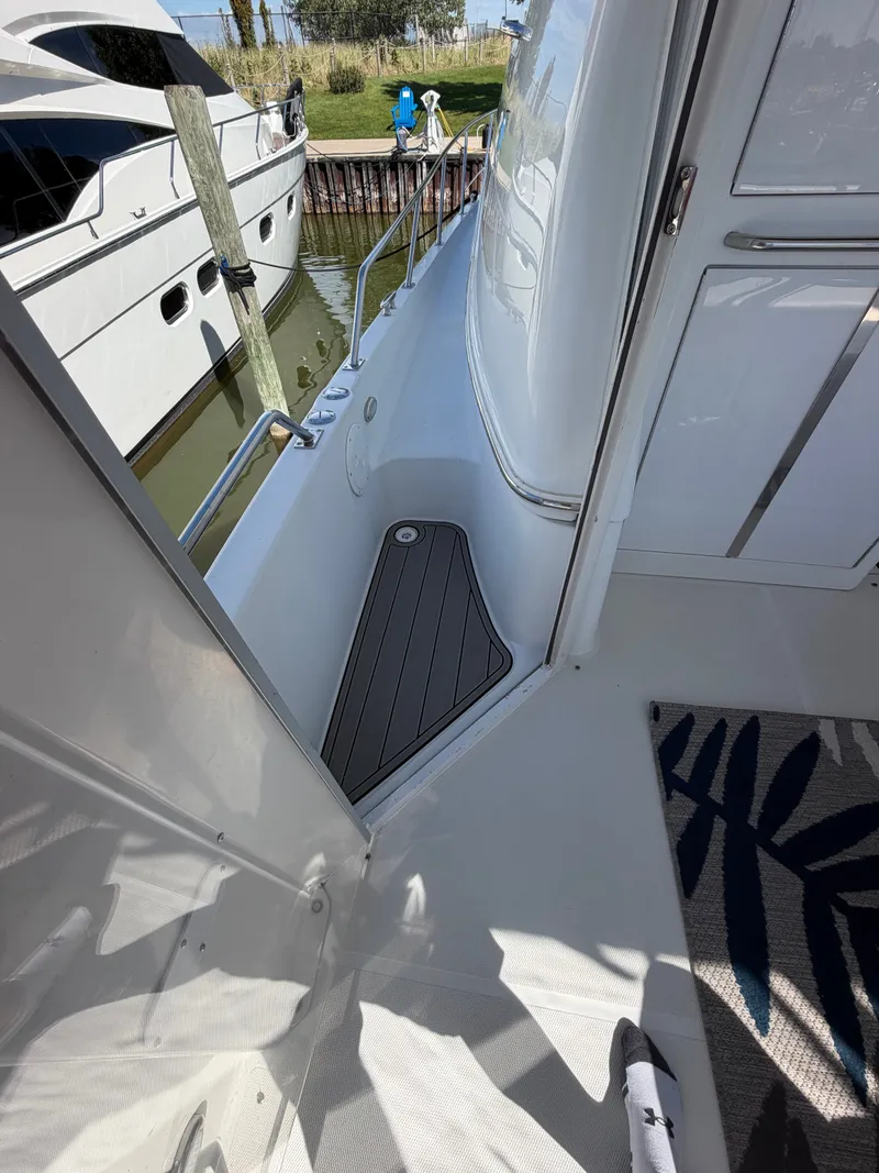 Slide: The Image of A narrow walkway on a yacht with white railing and gray flooring. - 30