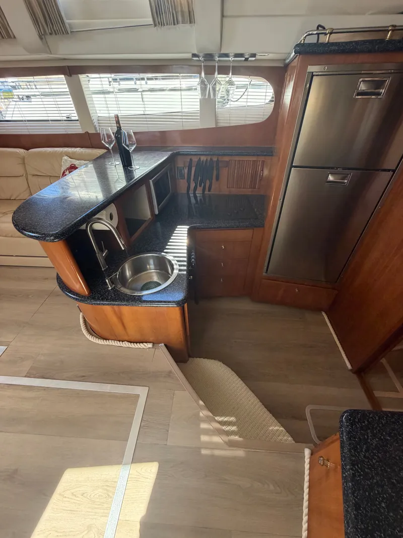 Slide: The Image of Interior of a 2000 Carver 396 Motor Yacht featuring a kitchen area with sink and refrigerator. - 43