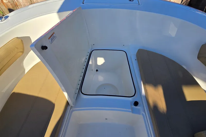 Slide: The Image of 2023 Bayliner Trophy T24CC boat interior with open storage compartment and cushioned seating. - 22
