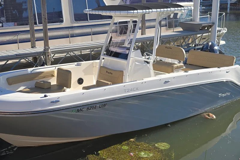 The Image of Bayliner Trophy T24CC 2023 at dock with T-top and beige seating area. - 0