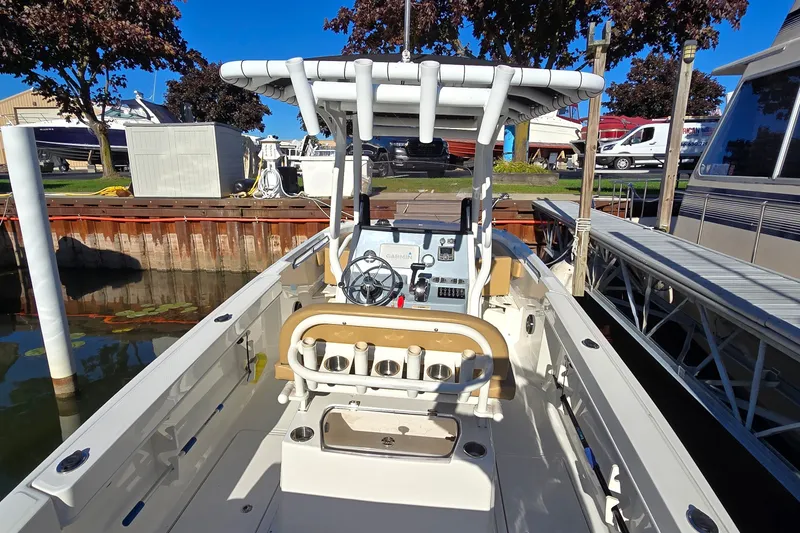 Slide: The Image of 2023 Bayliner Trophy T24CC boat docked, showcasing helm and seating area under clear blue sky. - 20